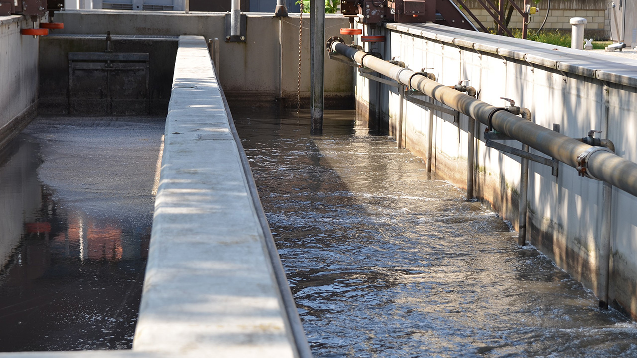 Vorklärbecken mit Wasser und Rohrleitungen in der Kläranlage Hersbruck
